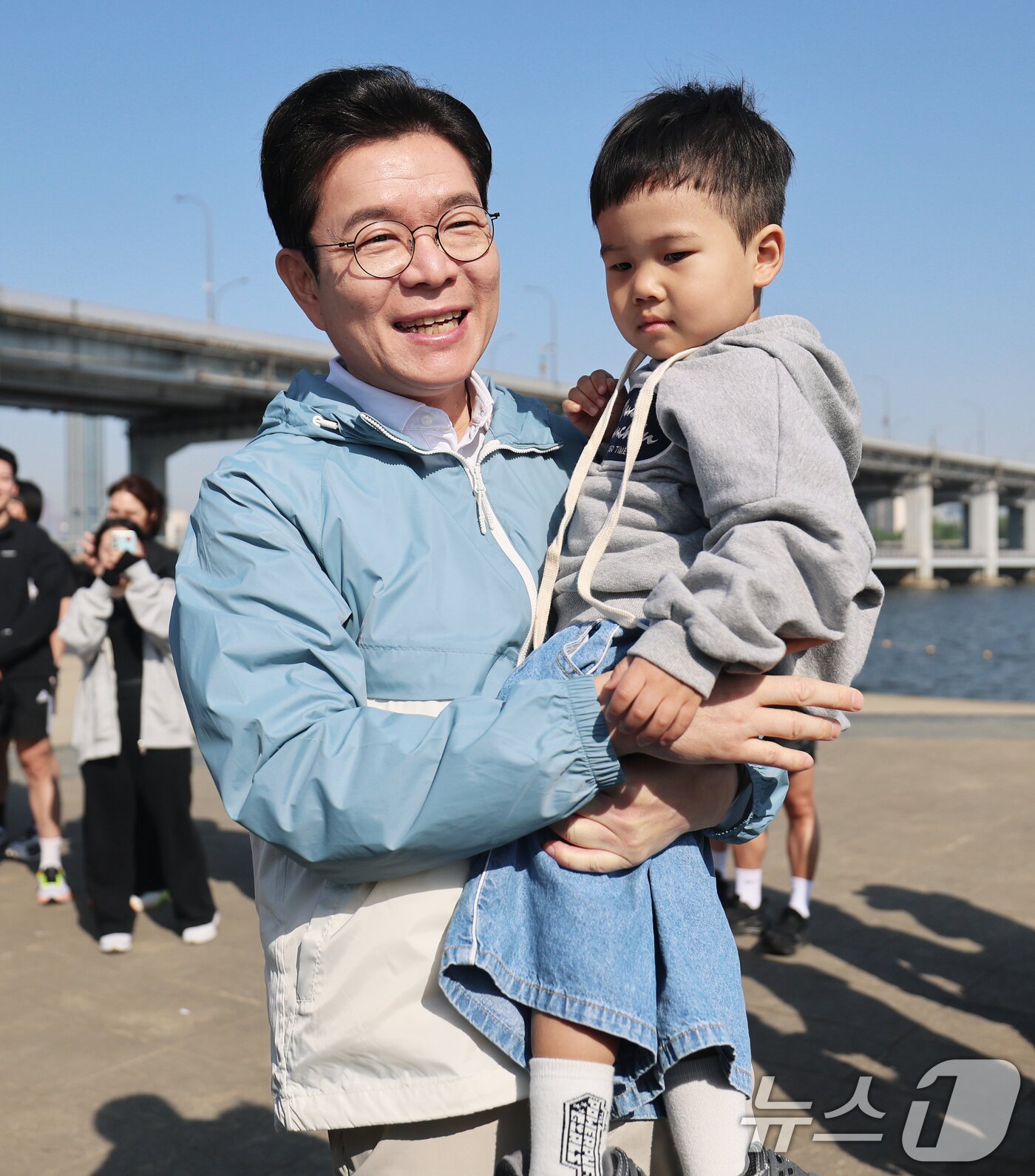 본문 이미지 - 정원오 더불어민주당 서울시장 후보가 25일 오전 서울 서초구 반포한강공원에서 열린 '찾아가는 현장: 러닝편'에서 러닝 동호회원 가족과 인사하며 아이를 안아주고 있다. 2026.4.25 ⓒ 뉴스1 오대일 기자