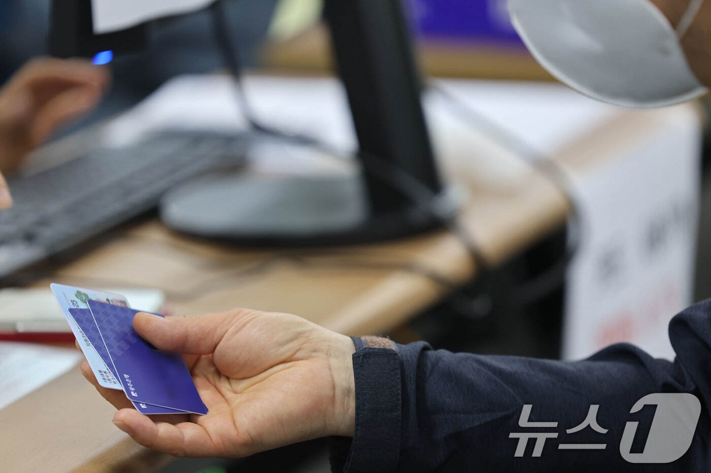 본문 이미지 - 최대 60만원 상당의 고유가 피해지원금 1차 지급이 시작된 27일 오전 광주 북구 두암3동 행정복지센터에서 한 시민이 신청을 마치고 카드를 받고 있다. 2026.4.27 ⓒ 뉴스1 박지현 기자