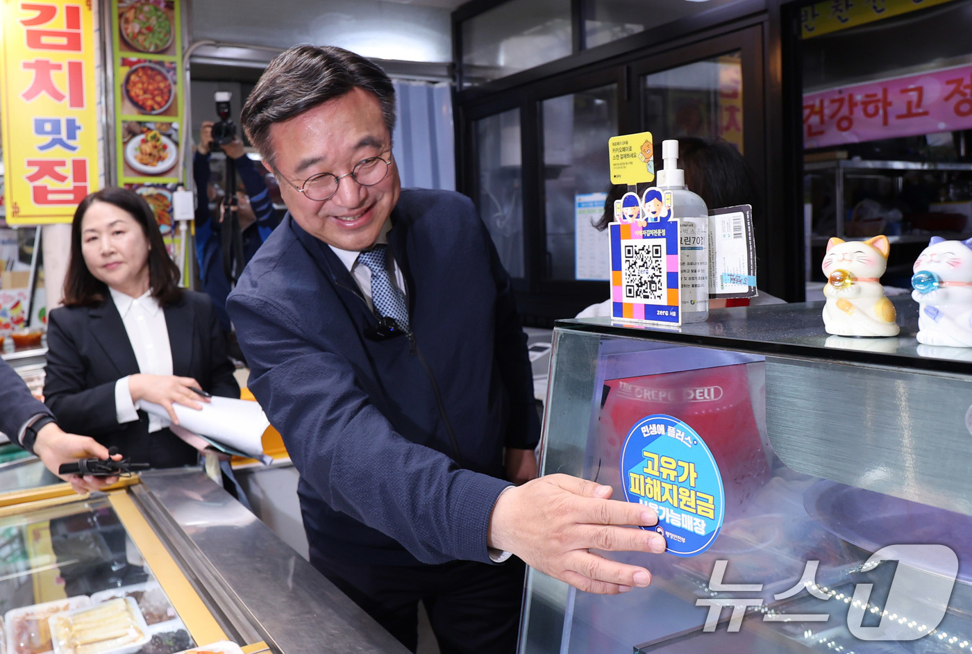 (서울=뉴스1) 박지혜 기자 = 윤호중 행정안전부 장관이 27일 서울 강서구 남부골목시장 한 매장을 찾아 '고유가 피해지원금 사용가능매장' 스티커를 붙이고 있다.이날 중동 전쟁으로 …