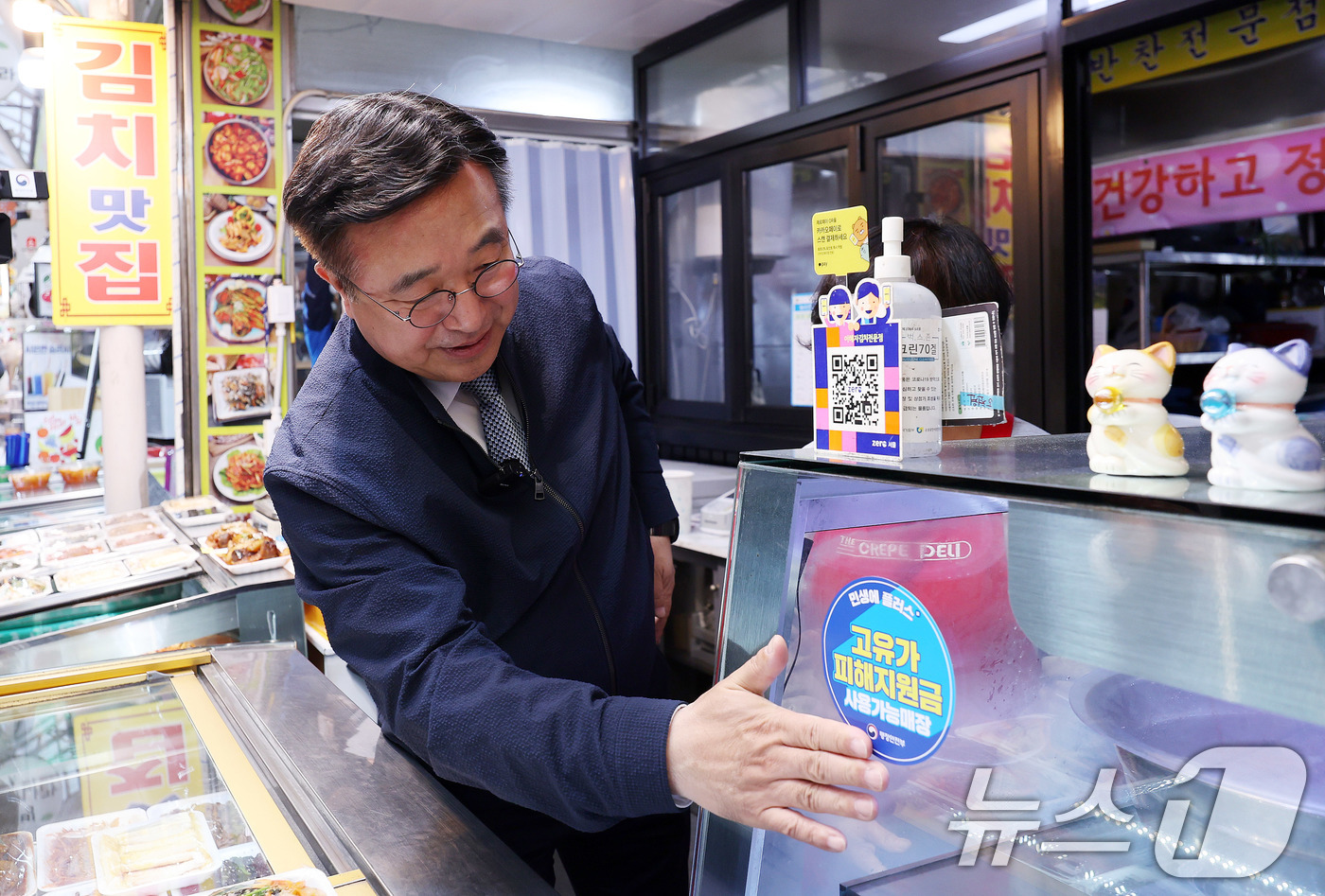 (서울=뉴스1) 박지혜 기자 = 윤호중 행정안전부 장관이 27일 서울 강서구 남부골목시장 한 매장을 찾아 '고유가 피해지원금 사용가능매장' 스티커를 붙이고 있다.이날 중동 전쟁으로 …