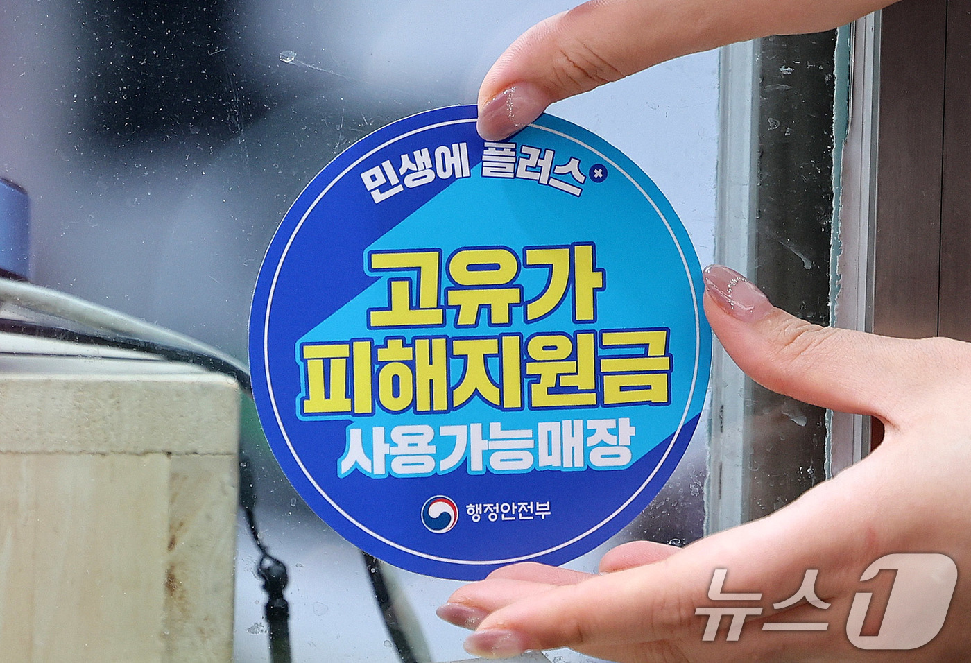 (서울=뉴스1) 박지혜 기자 = 고유가 피해지원금 1차 지급이 시작된 27일 서울 강서구 남부골목시장에서 한 상인이 '고유가 피해지원금 사용가능매장' 스티커를 붙이고 있다. 202 …