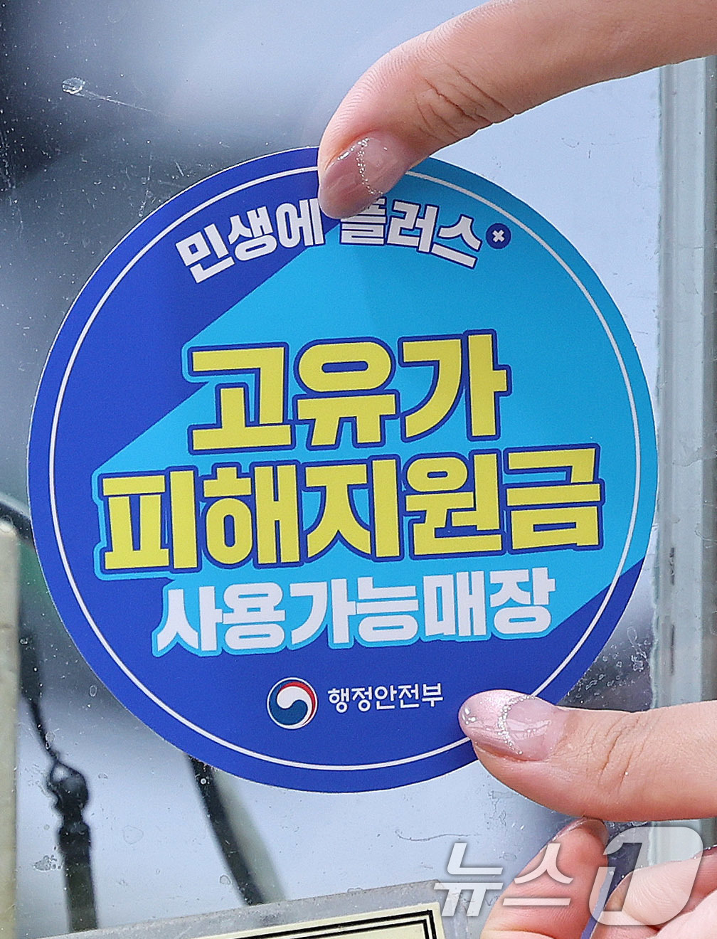 (서울=뉴스1) 박지혜 기자 = 고유가 피해지원금 1차 지급이 시작된 27일 서울 강서구 남부골목시장에서 한 상인이 '고유가 피해지원금 사용가능매장' 스티커를 붙이고 있다. 202 …