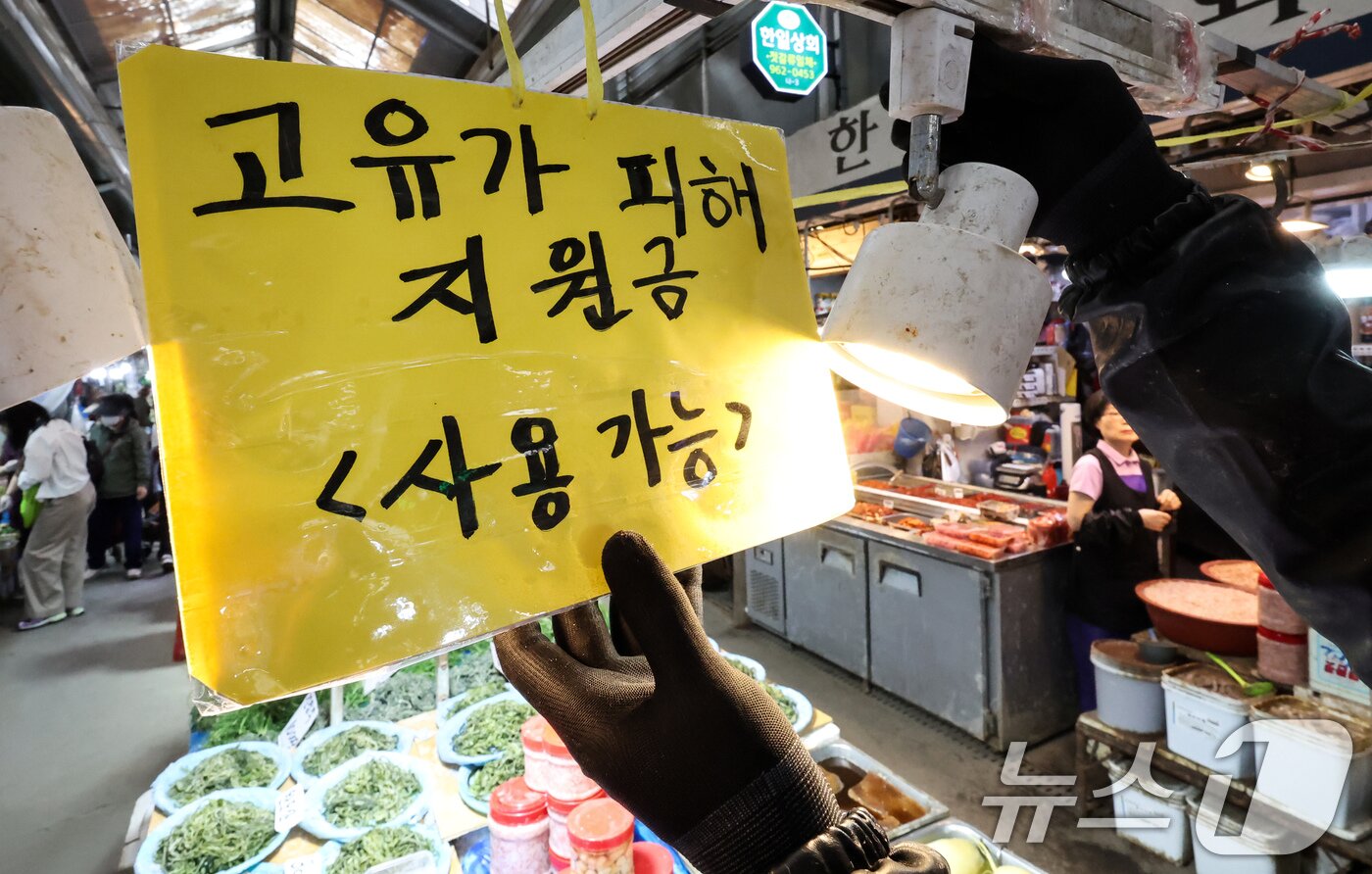 본문 이미지 - 고유가 피해지원금 1차 지급 신청일인 27일 서울 동대문구 경동시장 한 점포에서 직원이 ’고유가 피해지원금 사용 가능‘ 안내문을 게시하고 있다. 피해지원금 대상은 소득 하위 70% 국민에게 1인당 10만~60만원을 차등 지원하며 1차 지급 대상자는 기초생활수급자, 차상위계층·한부모가족 등 취약계층이다. 신청 첫 주에는 혼잡 및 시스템 과부하를 막기 위해 출생 연도 끝자리를 기준으로 요일제가 적용되며 오는 5월 8일 오후 6시까지 약 2주간 온오프라인으로 신청할 수 있다. 2026.4.27 ⓒ 뉴스1 임지훈 인턴기자