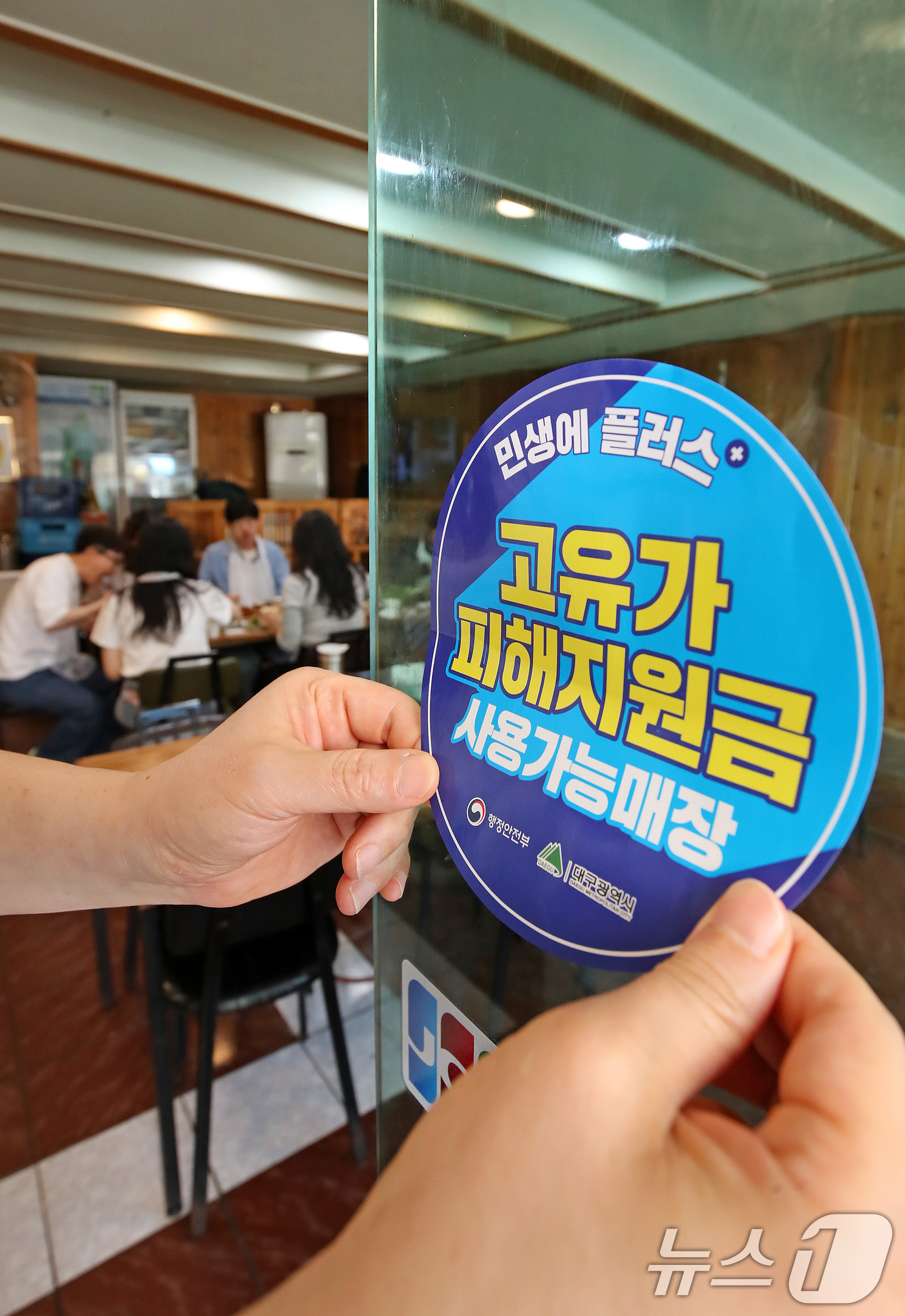 (대구=뉴스1) 공정식 기자 = 고유가 피해지원금 1차 지급이 시작된 27일 대구 수성구 한 음식점에서 상인이 고유가 피해지원금 사용 가능 매장을 알리는 스티커를 붙이고 있다. 2 …