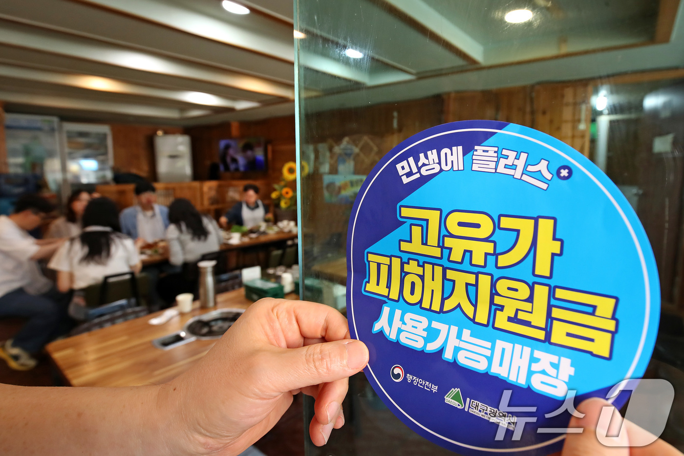 (대구=뉴스1) 공정식 기자 = 고유가 피해지원금 1차 지급이 시작된 27일 대구 수성구 한 음식점에서 상인이 고유가 피해지원금 사용 가능 매장을 알리는 스티커를 붙이고 있다. 2 …