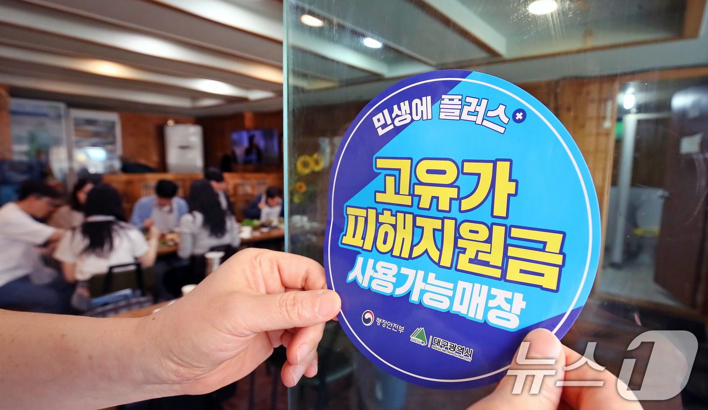 (대구=뉴스1) 공정식 기자 = 고유가 피해지원금 1차 지급이 시작된 27일 대구 수성구 한 음식점에서 상인이 고유가 피해지원금 사용 가능 매장을 알리는 스티커를 붙이고 있다. 2 …