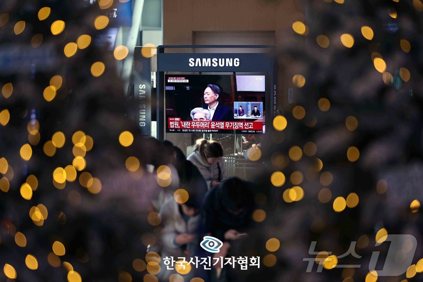 본문 이미지 - '빛의 혁명'으로부터 서울역 대합실에 설치된 TV를 통해 윤석열 전 대통령의 내란 우두머리 혐의 1심 선고 관련 뉴스가 나오고 있다. 윤 전 대통령은 2024년 12월 3일 비상계엄을 선포한 지 443일 만에 무기징역을 선고받았다. 2026.4.27 ⓒ 뉴스1  구윤성 기자