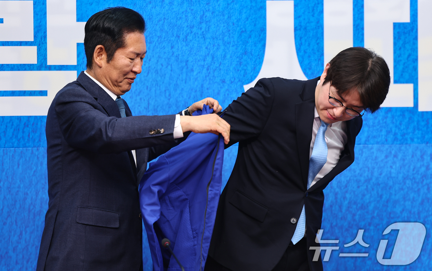 (서울=뉴스1) 김도우 기자 = 정청래 더불어민주당 대표가 29일 서울 여의도 국회에서 열린 더불어민주당 인재영입식에서 하정우 전 청와대 AI미래기획수석에게 당 점퍼를 입혀주고 있 …