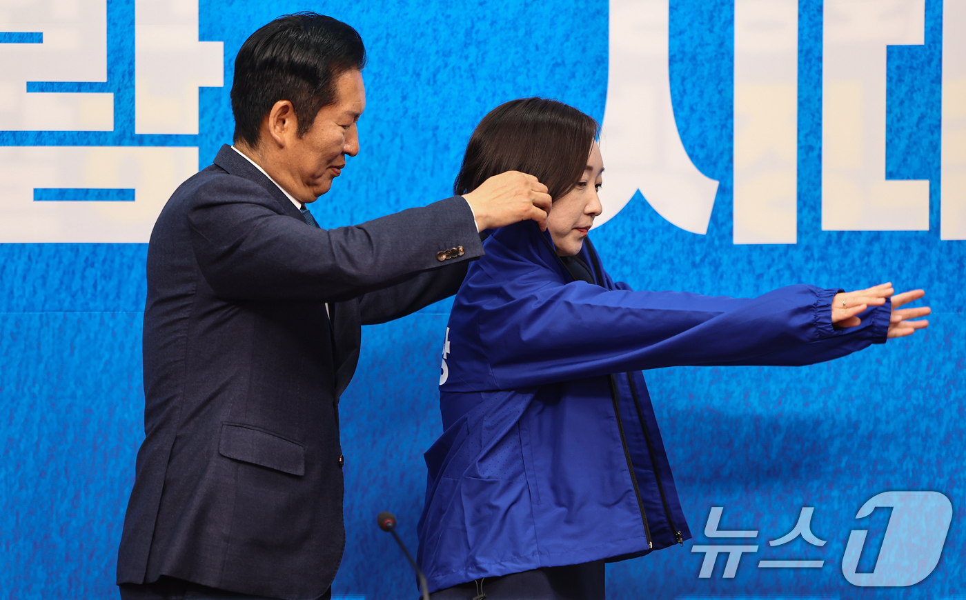 (서울=뉴스1) 김도우 기자 = 정청래 더불어민주당 대표가 29일 서울 여의도 국회에서 열린 더불어민주당 인재영입식에서 전은수 전 청와대 대변인에게 당 점퍼를 입혀주고 있다. 20 …