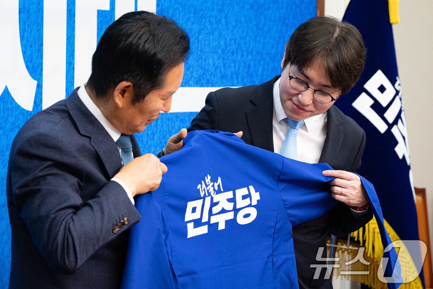 본문 이미지 - 더불어민주당 6.3 지방선거 인재영입 2호 하정우 전 청와대 AI미래기획수석이 29일 서울 여의도 국회에서 열린 제2차 인재영입식에서 정청래 대표와 더불어민주당 점퍼를 바라보고 있다. 하정우 전 수석은 전재수 의원이 당 부산시장 후보로 선출되면서 공석이 된 부산 북구갑 지역구에, 전은수 전 대변인은 강훈식 대통령 비서실장의 지역구였던 충남 아산을에 출마할 전망이다. ⓒ 뉴스1 유승관 기자