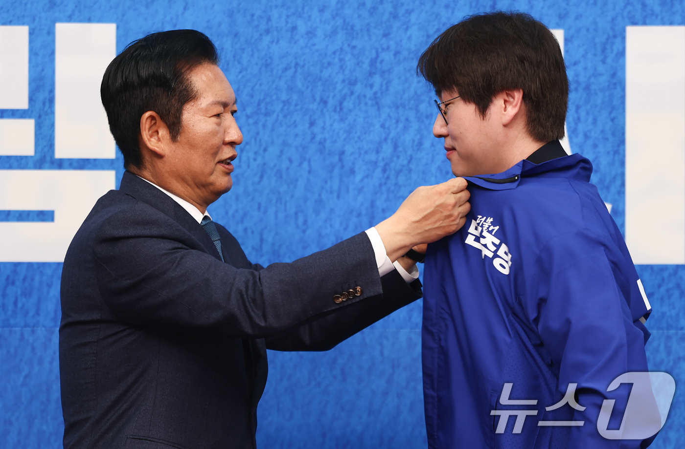 (서울=뉴스1) 김도우 기자 = 정청래 더불어민주당 대표가 29일 서울 여의도 국회에서 열린 더불어민주당 인재영입식에서 전은수 전 청와대 대변인에게 당 점퍼를 입혀주고 있다. 20 …