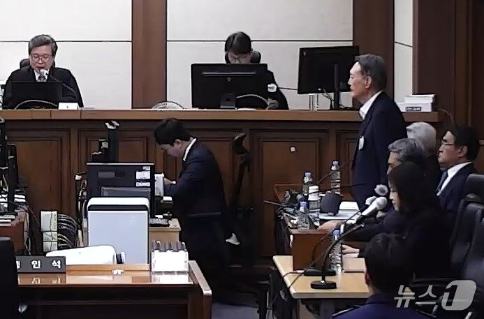본문 이미지 - 특수공무집행방해·직권남용 권리행사방해 등의 혐의를 받는 윤석열 전 대통령이 29일 서울 서초구 서울고등법원에서 열린 항소심 선고공판에서 자리에서 일어나 주문을 듣고 있다. (서울고등법원 제공 영상 캡쳐. 재판매 및 DB 금지) 2026.4.29 ⓒ 뉴스1 오대일 기자