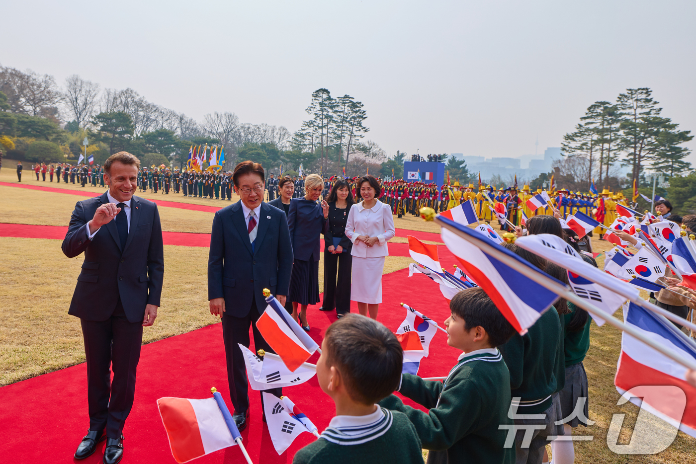 (서울=뉴스1) 허경 기자 = 이재명 대통령 부부와 에마뉘엘 마크롱 프랑스 대통령 부부가 3일 청와대에서 열린 공식 환영식에서 어린이들에게 인사를 하고 있다. (청와대 제공. 재판 …