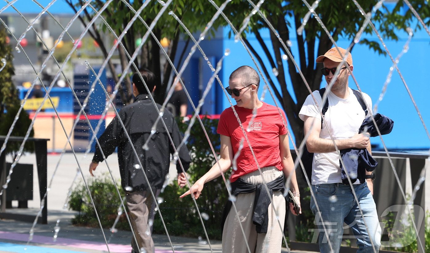 (서울=뉴스1) 임지훈 인턴기자 = 서울 낮 최고 기온이 22도까지 오르는 등 따듯한 봄 날씨를 보인 30일 서울 종로구 광화문광장을 찾은 외국인 관광객들이 분수 터널을 지나가고 …