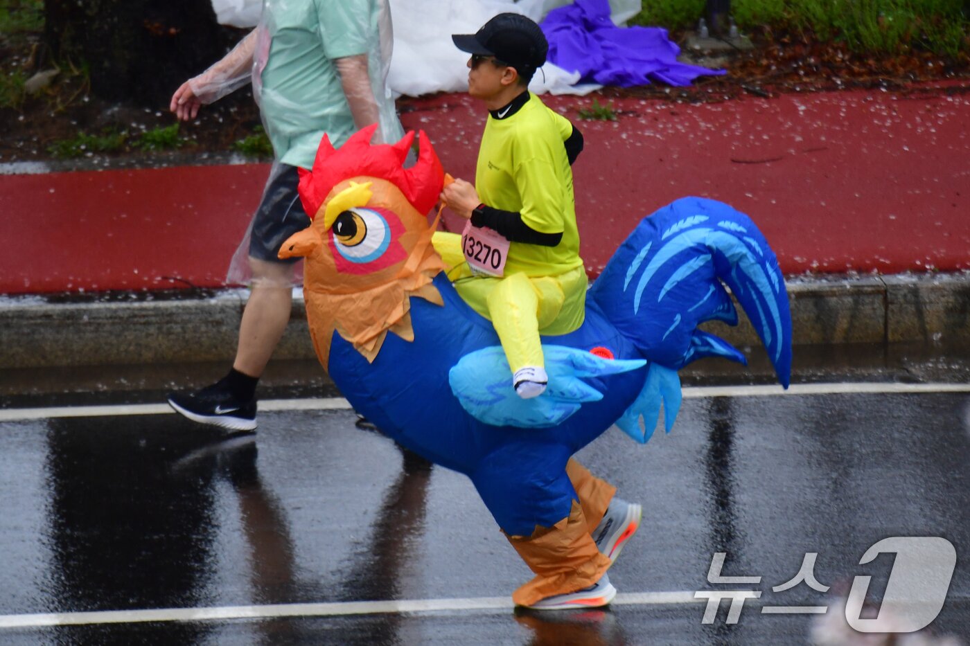 본문 이미지 - 4일 경북 경주시 보문단지에서 열린 제33회 경주벚꽃미라톤 대회에서 닭 캐릭터 복장을 한 참가자가 힘차게 달리고 있다. 2026.4.4 ⓒ 뉴스1 최창호 기자