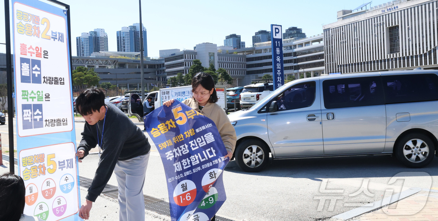 (세종=뉴스1) 김기남 기자 = 7일 세종시 정부세종청사 주차장에서 정부청사관리본부 직원들이 공공기관 차량2부제 및 방문차량 5부제 시행을 알리는 안내문을 게시하고 있다.중동 전쟁 …