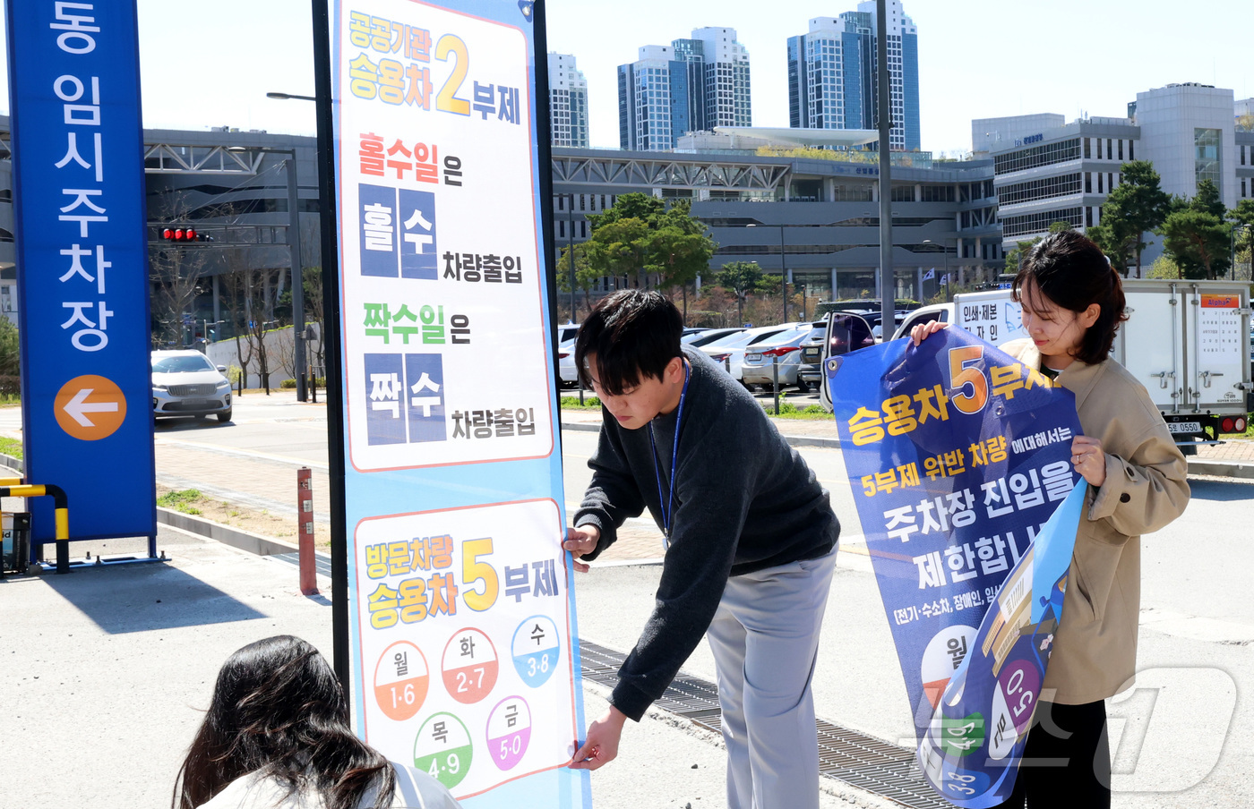 (세종=뉴스1) 김기남 기자 = 7일 세종시 정부세종청사 주차장에서 정부청사관리본부 직원들이 공공기관 차량2부제 및 방문차량 5부제 시행을 알리는 안내문을 게시하고 있다.중동 전쟁 …