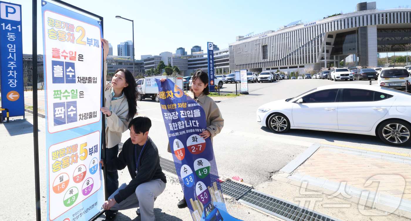 (세종=뉴스1) 김기남 기자 = 7일 세종시 정부세종청사 주차장에서 정부청사관리본부 직원들이 공공기관 차량2부제 및 방문차량 5부제 시행을 알리는 안내문을 게시하고 있다.중동 전쟁 …