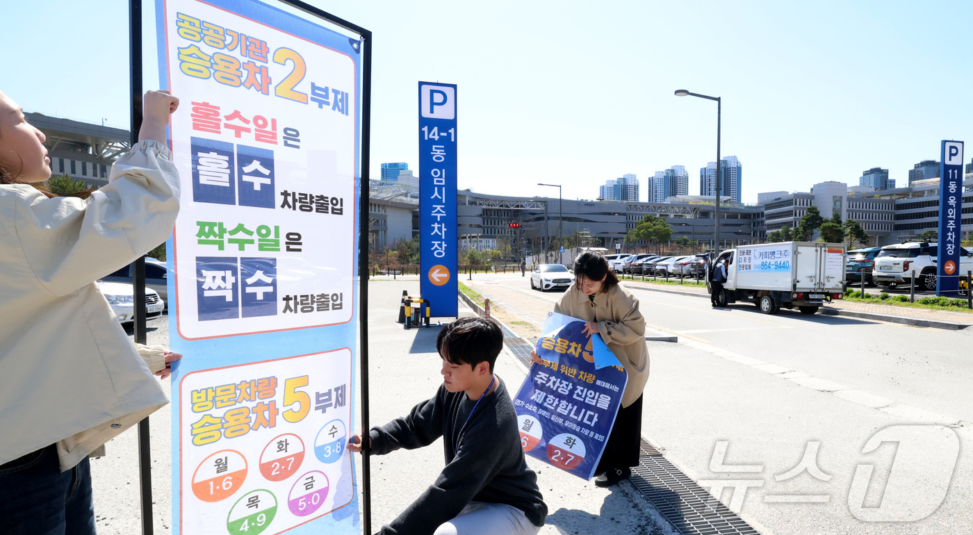 (세종=뉴스1) 김기남 기자 = 7일 세종시 정부세종청사 주차장에서 정부청사관리본부 직원들이 공공기관 차량2부제 및 방문차량 5부제 시행을 알리는 안내문을 게시하고 있다.중동 전쟁 …