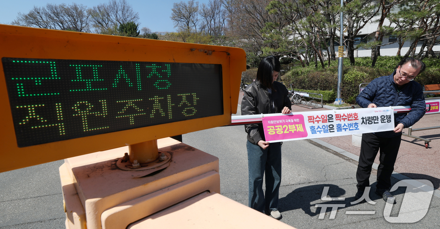 (군포=뉴스1) 김영운 기자 = 공공기관 승용차 2부제 시행을 하루 앞둔 7일 경기 군포시 금정동 군포시청 직원주차장에서 직원들이 공공기관 2부제를 알리는 현수막을 부착하고 있다. …