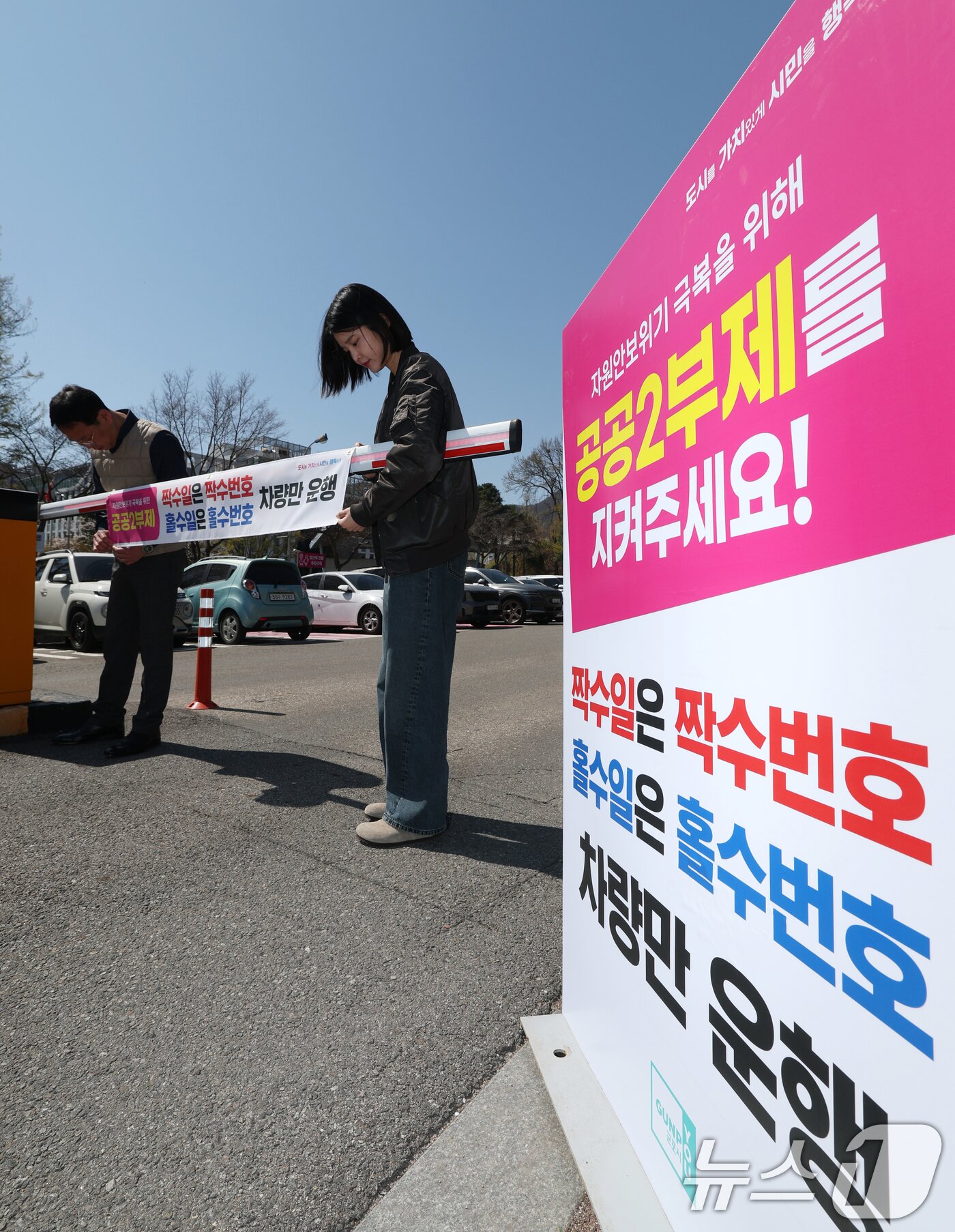 본문 이미지 - 공공기관 승용차 2부제 시행을 하루 앞둔 7일 경기 군포시 금정동 군포시청 직원주차장에서 직원들이 공공기관 2부제를 알리는 현수막을 부착하고 있다. 2026.4.7 ⓒ 뉴스1 김영운 기자
