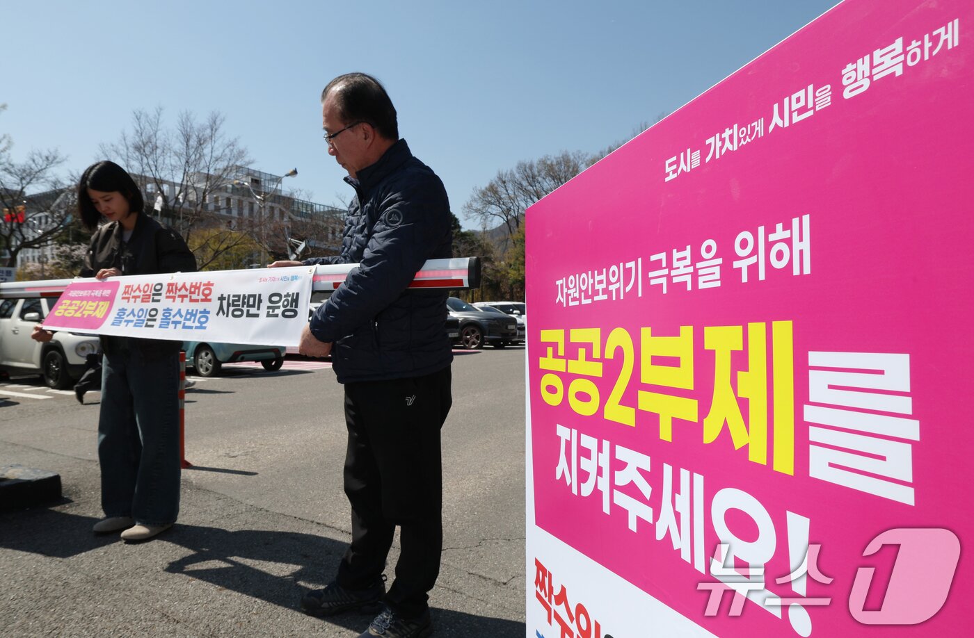 본문 이미지 - 공공기관 승용차 2부제 시행을 하루 앞둔 7일 경기 군포시 금정동 군포시청 직원주차장에서 직원들이 공공기관 2부제를 알리는 현수막을 부착하고 있다. 2026.4.7 ⓒ 뉴스1 김영운 기자