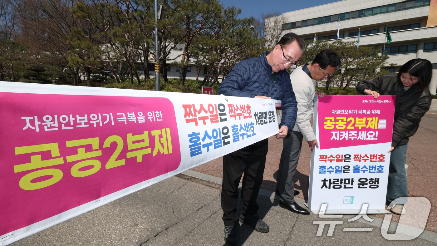본문 이미지 - 공공기관 승용차 2부제 시행을 하루 앞둔 7일 경기 군포시 금정동 군포시청 직원주차장에서 직원들이 공공기관 2부제를 알리는 현수막을 부착하고 있다.  2026.4.7 ⓒ 뉴스1 김영운 기자