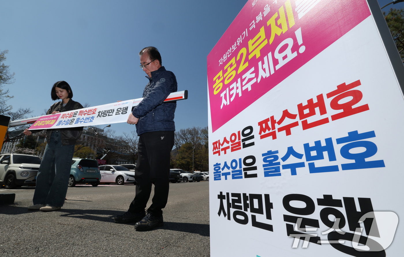 (군포=뉴스1) 김영운 기자 = 공공기관 승용차 2부제 시행을 하루 앞둔 7일 경기 군포시 금정동 군포시청 직원주차장에서 직원들이 공공기관 2부제를 알리는 현수막을 부착하고 있다. …