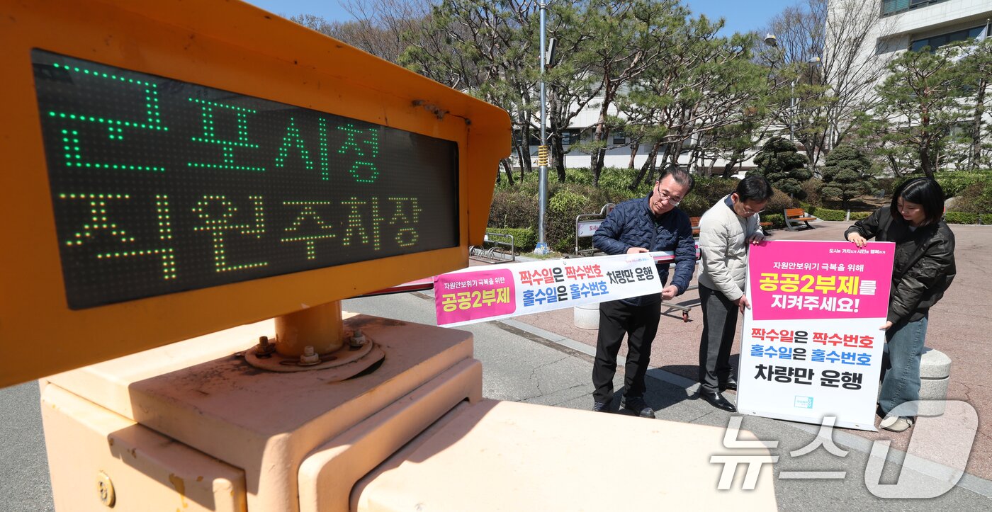 본문 이미지 - 공공기관 승용차 2부제 시행을 하루 앞둔 7일 경기 군포시 금정동 군포시청 직원주차장에서 직원들이 공공기관 2부제를 알리는 현수막을 부착하고 있다. 2026.4.7 ⓒ 뉴스1 김영운 기자