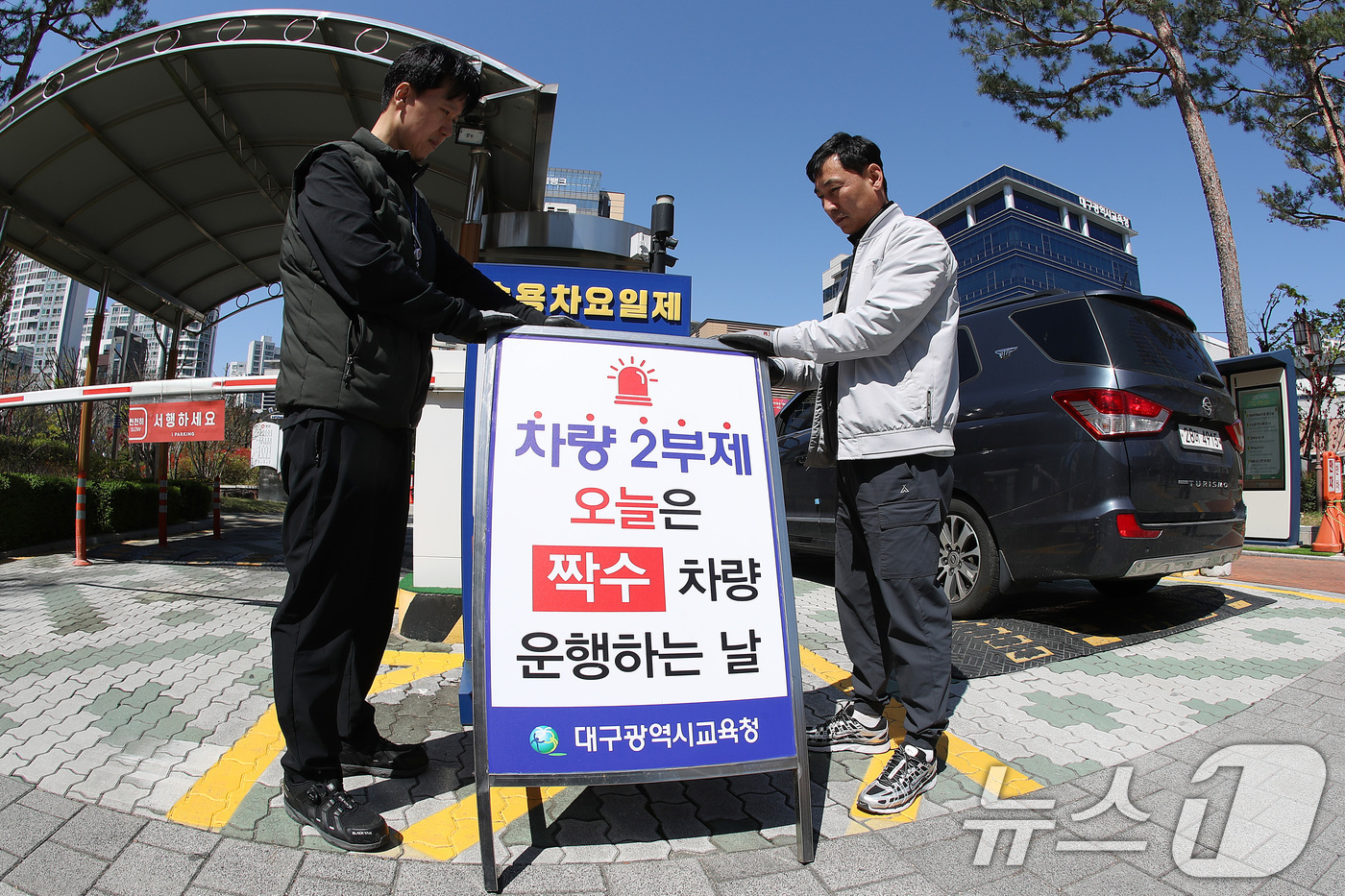 (대구=뉴스1) 공정식 기자 = '공공기관 차량 2부제' 시행을 하루 앞둔 7일 오후 대구시교육청 관계자들이 정문 차량 출입구에 차량 2부제를 알리는 입간판을 설치하고 있다. 20 …