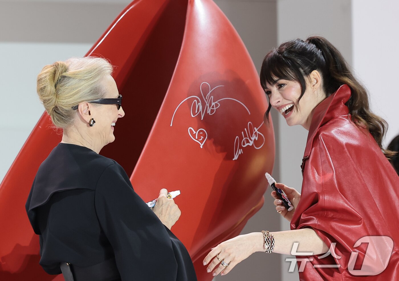 본문 이미지 - 배우 앤 해서웨이와 메릴 스트립(왼쪽)이 8일 서울 영등포구 타임스퀘어에서 열린 영화 ‘악마는 프라다를 입는다 2’(감독 데이빗 프랭클) 레드카펫 행사에서 구두에 사인을 한 뒤 포즈를 취하고 있다. 2026.4.8 ⓒ 뉴스1 권현진 기자