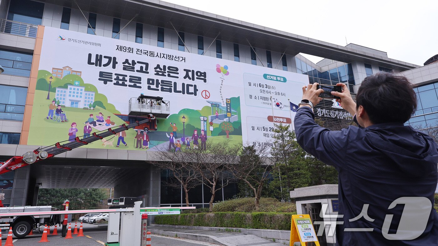 본문 이미지 - 제9회 전국동시지방선거를 앞둔 9일 경기도 수원시 영통구 경기도선거관리위원회 청사 외벽에 관계자들이 투표참여를 독려하는 대형 현수막을 설치하고 있다. 2026.4.9 ⓒ 뉴스1 박지혜 기자