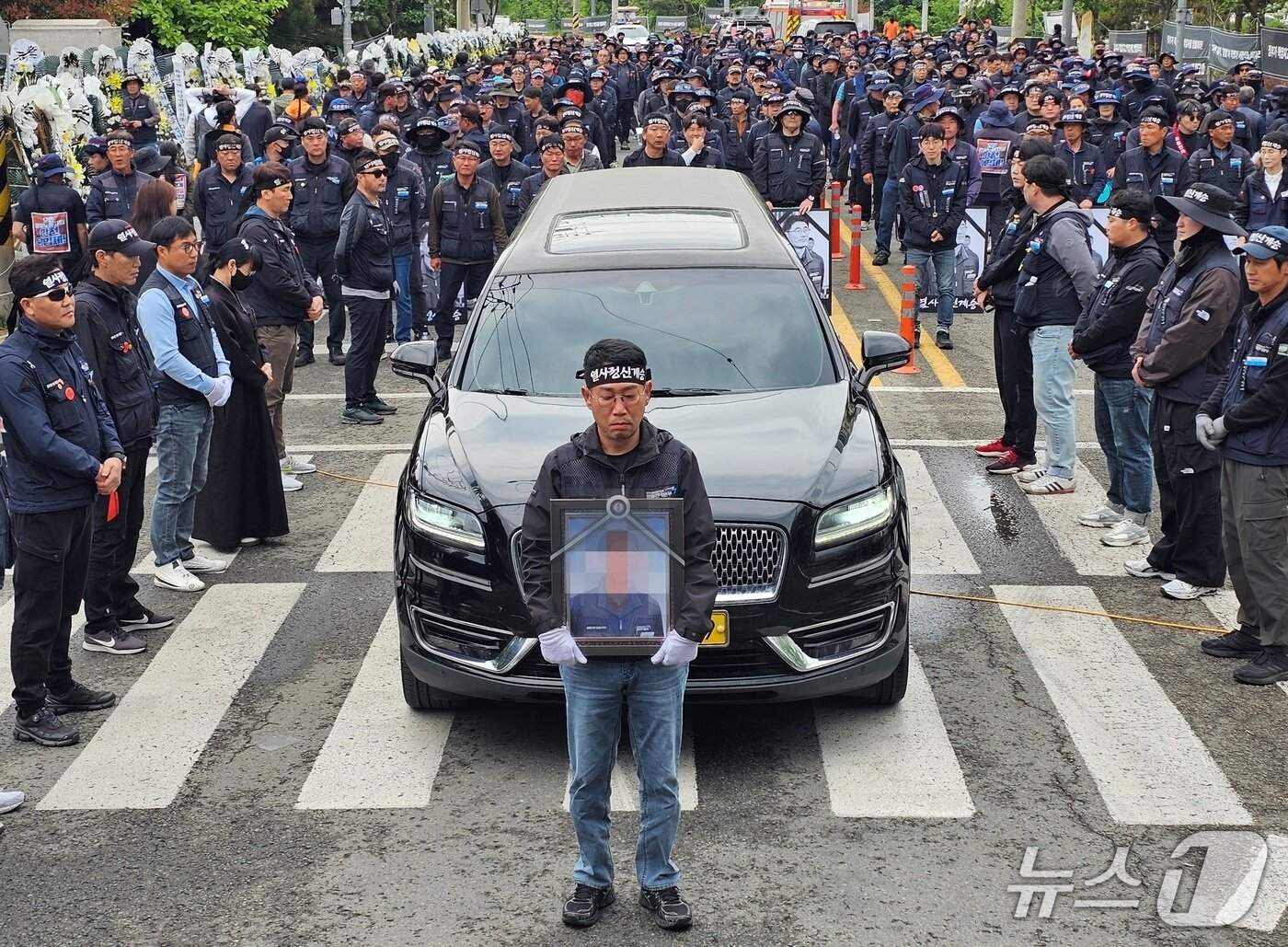 본문 이미지 - 김동국 민주노총 화물연대 위원장이 1일 숨진 조합원 A 씨 추모제에서 A 씨 영정 사진을 운구차 앞에서 들고 있다. 2026.5.1/뉴스1 한송학기자