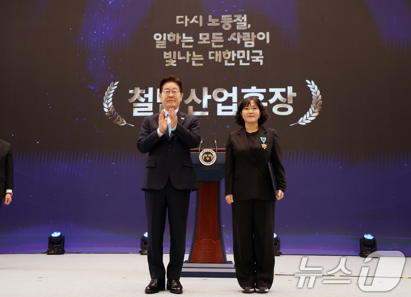 (서울=뉴스1) 허경 기자 = 이재명 대통령이 1일 청와대 영빈관에서 열린 2026 노동절 기념식에서 염정열 전국언론노조 방송작가지부장에게 철탑산업훈장을 수여하고 기념촬영을 하고 …