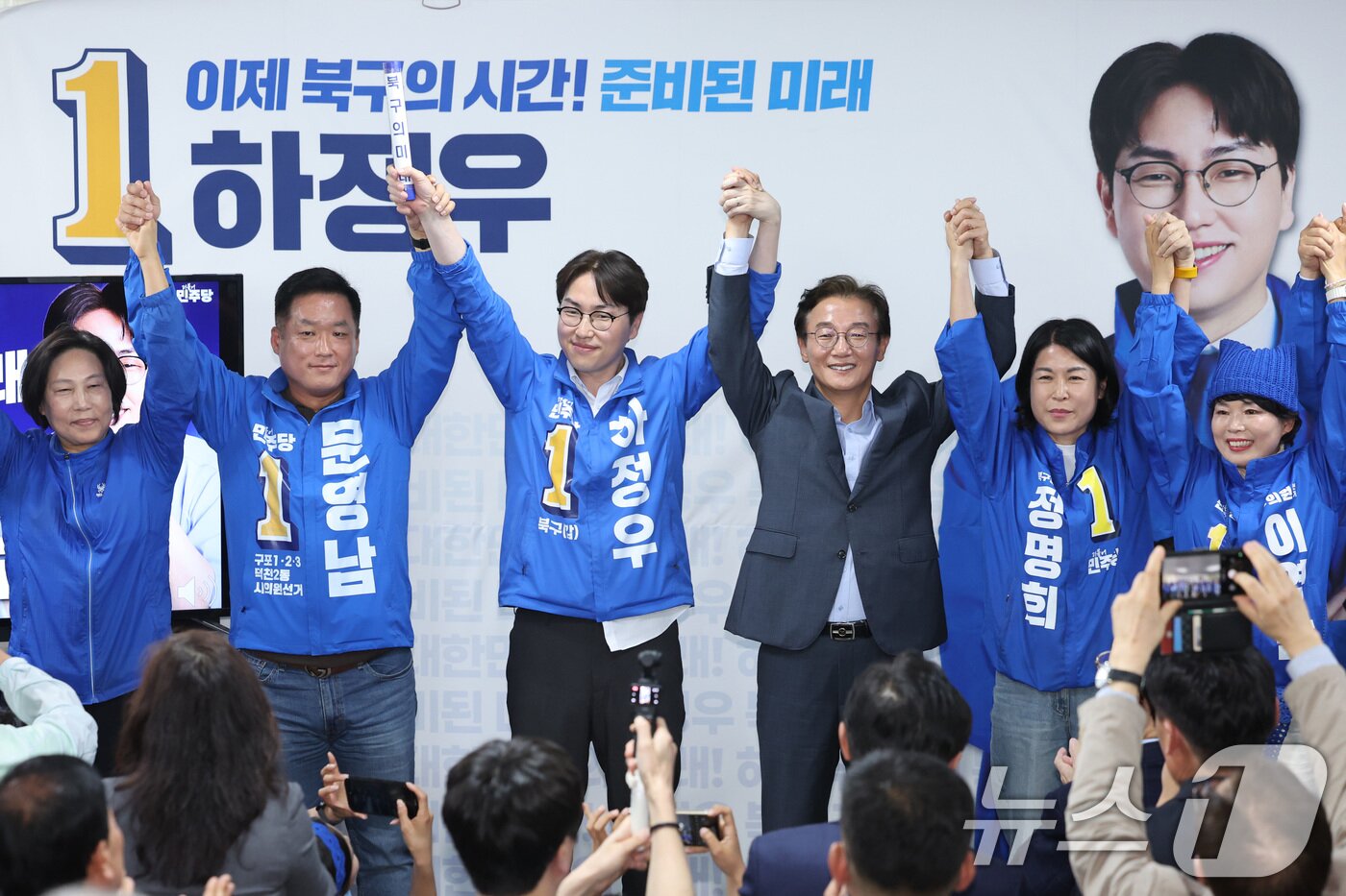 본문 이미지 - 부산 북갑 국회의원 보궐선거에 출마한 하정우 더불어민주당 후보가 10일 부산 북구 자신의 선거사무소 개소식에서 전재수 부산시장 후보 등과 함께 손을 잡고 지지자들에게 인사하고 있다. 2026.5.10 ⓒ 뉴스1 신웅수 기자