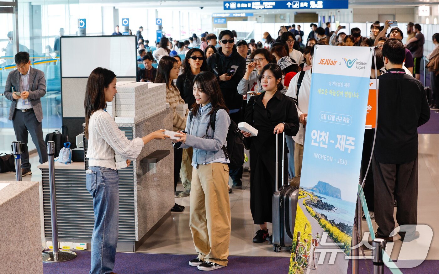 본문 이미지 - 인천-제주 국내선 직항노선이 10년만에 운영을 재개한 12일 인천국제공항 1터미널에서 제주로 향하는 제주항공 승객들이 기념품을 받고 있다. 2026.5.12 ⓒ 뉴스1 안은나 기자