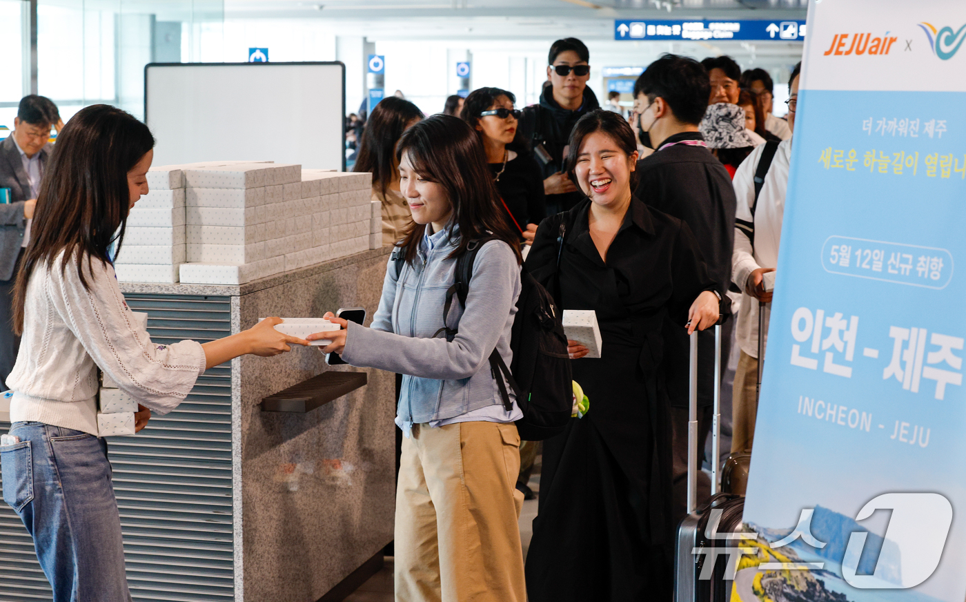 (인천공항=뉴스1) 안은나 기자 = 인천-제주 국내선 직항노선이 10년만에 운영을 재개한 12일 인천국제공항 1터미널에서 제주로 향하는 제주항공 승객들이 기념품을 받고 있다. 20 …
