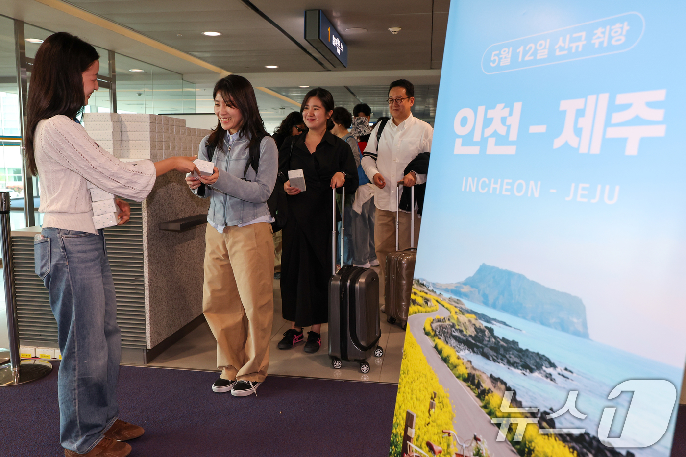 (인천공항=뉴스1) 안은나 기자 = 인천-제주 국내선 직항노선이 10년만에 운영을 재개한 12일 인천국제공항 1터미널에서 제주로 향하는 제주항공 승객들이 기념품을 받고 있다. 20 …