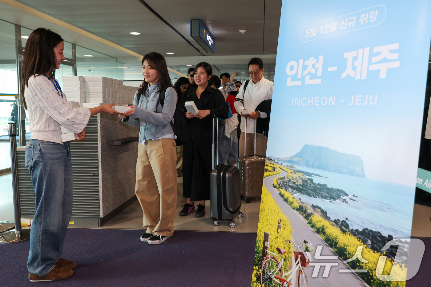 (인천공항=뉴스1) 안은나 기자 = 인천-제주 국내선 직항노선이 10년만에 운영을 재개한 12일 인천국제공항 1터미널에서 제주로 향하는 제주항공  승객들이 기념품을 받고 있다. 2 …