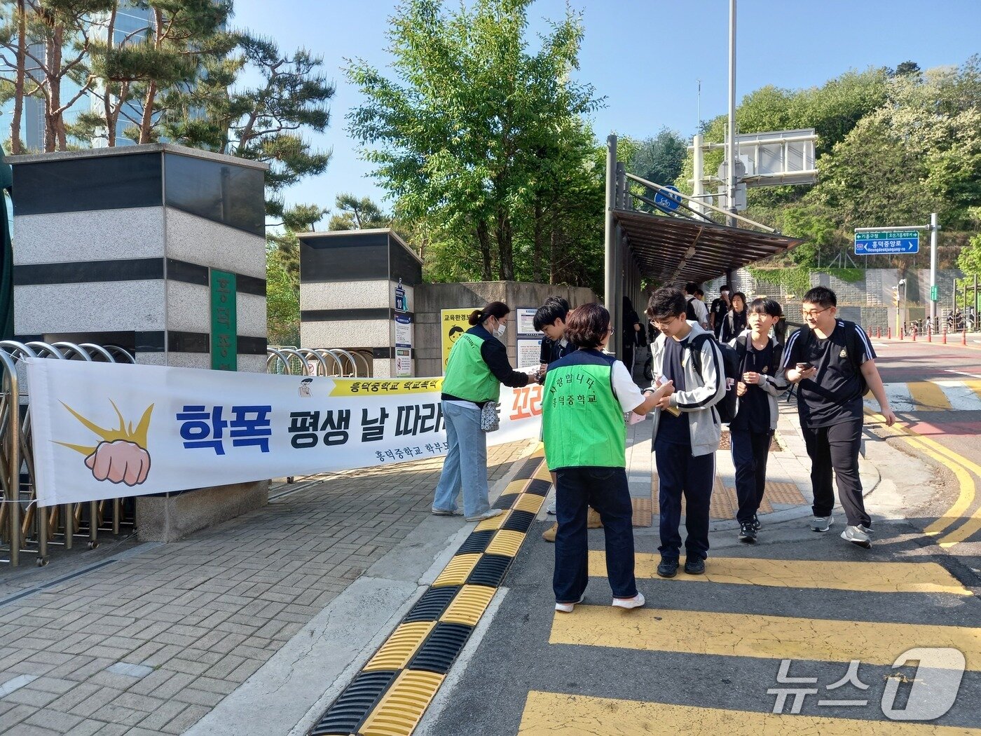 본문 이미지 - 용인 흥덕중학교가 지난 13일 진행한 사이버 폭력 예방 캠페인에서 참가자들이 등교하는 학생들에게 학교 폭력 예방 문구가 적힌 약과를 전달하고 있다.(흥덕중 제공)