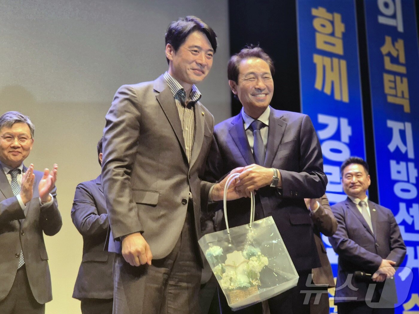 본문 이미지 - 한준호 민주당 의원이 15일 강원 강릉 단오제전수교육관 공연동에서 열린 우상호 강원도지사 후보 선거대책위원회 출범식에서 자신을 정치로 이끌어준 우 후보에게 스승의날 꽃다발을 전달한 뒤 기념촬영을 하고 있다. 2026.5.15 ⓒ 뉴스1 윤왕근 기자