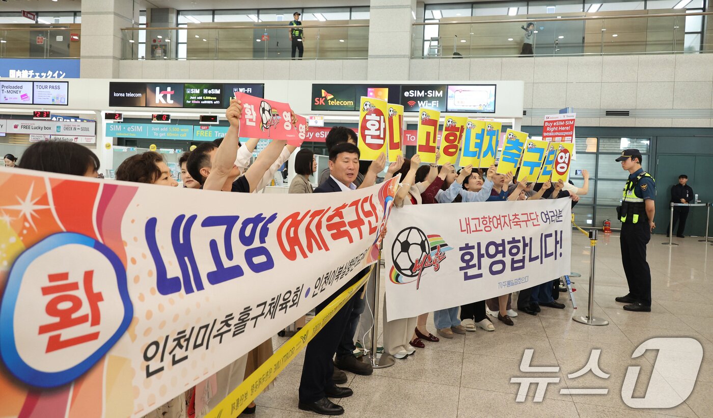 본문 이미지 - 북한 여자축구 최강팀인 내고향여자축구단이 입국하는 17일 인천국제공항 입국장에서 시민단체회원들이환영 현수막을 펼쳐 보이고 있다. 내고향여자축구단은 오는 20일 오후 7시 수원종합운동장에서 열리는 대회 4강에서 수원FC위민과 남북 대결을 펼친다. (공동취재) 2026.5.17 ⓒ 뉴스1 임세영 기자