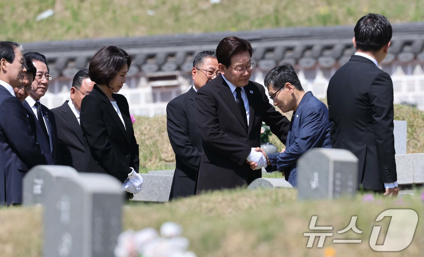 본문 이미지 - 이재명 대통령과 김혜경 여사가 18일 오전 광주 북구 운정동 국립 5·18민주묘지을 찾아 故 양창근 묘역에 헌화한 뒤 유가족을 위로하고 있다. 2026.5.18 ⓒ 뉴스1 이재명 기자
