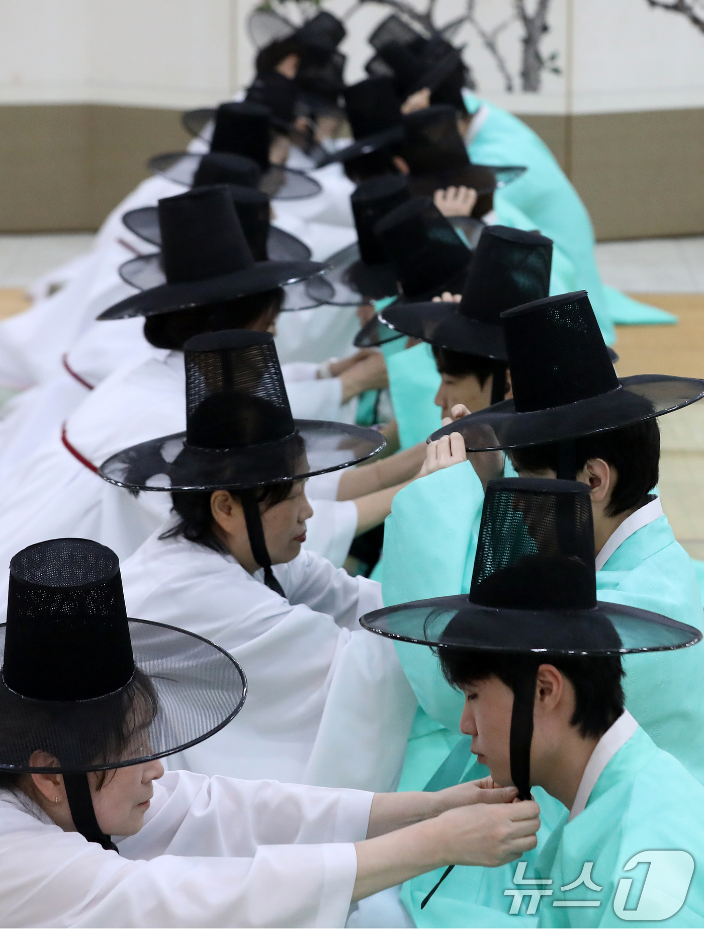 (부산=뉴스1) 윤일지 기자 = 성년의 날인 18일 오후 부산 사상구 부산시여성문화회관 대강당에서 열린 '전통 성년례'에서 남성 참가자들이 갓을 쓰는 관례 의식을 하고 있다.  2 …