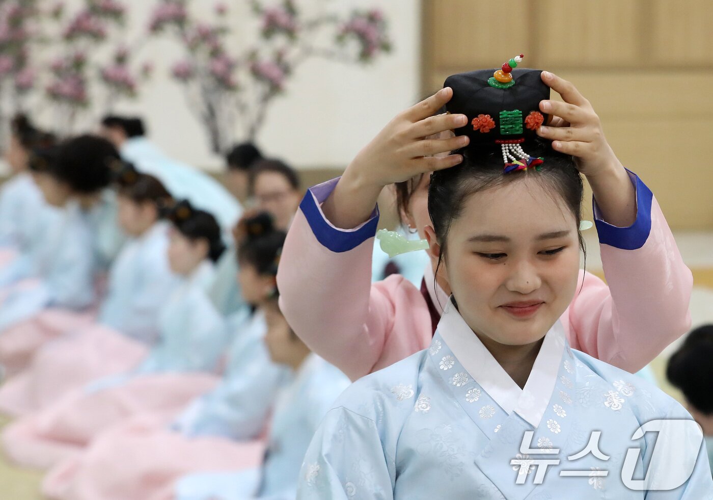 본문 이미지 - 성년의 날인 18일 오후 부산 사상구 부산시여성문화회관 대강당에서 열린 '전통 성년례'에서 여성 참가자들이 비녀를 꽂는 계례 의식을 하고 있다. 2026.5.18 ⓒ 뉴스1 윤일지 기자