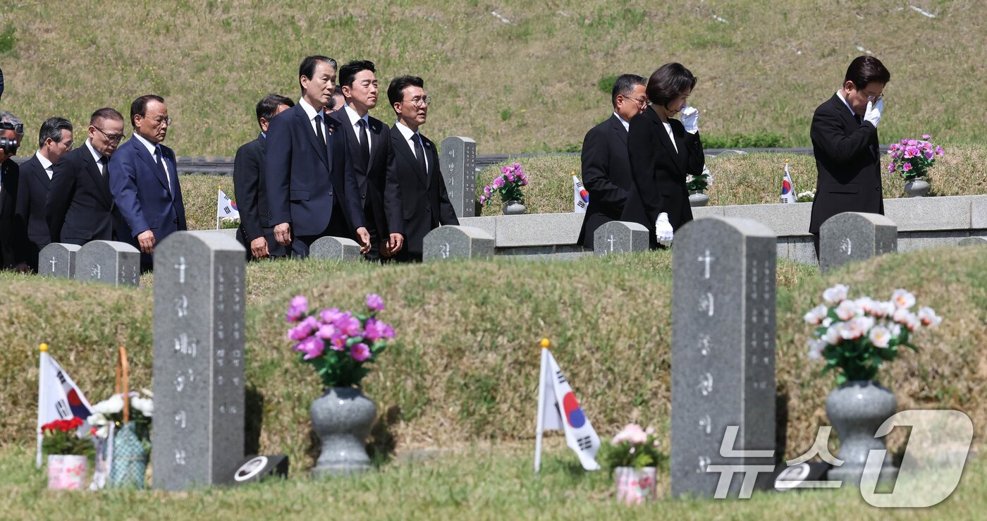 본문 이미지 - 이재명 대통령과 김혜경 여사가 18일 오전 광주 북구 운정동 국립 5·18민주묘지에서 눈물을 닦으며 이동하고 있다. 2026.5.18 ⓒ 뉴스1 이재명 기자