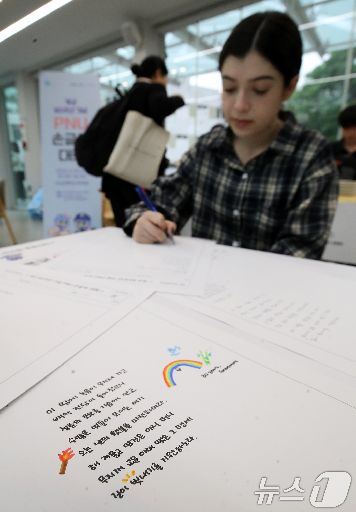 (부산=뉴스1) 윤일지 기자 = 20일 부산 금정구 부산대학교 운죽정에서 열린 '개교 80주년 기념 PNU 손글씨 대회'에서 외국인 유학생과 학생들이 손글씨 쓰고 있다.  2026 …