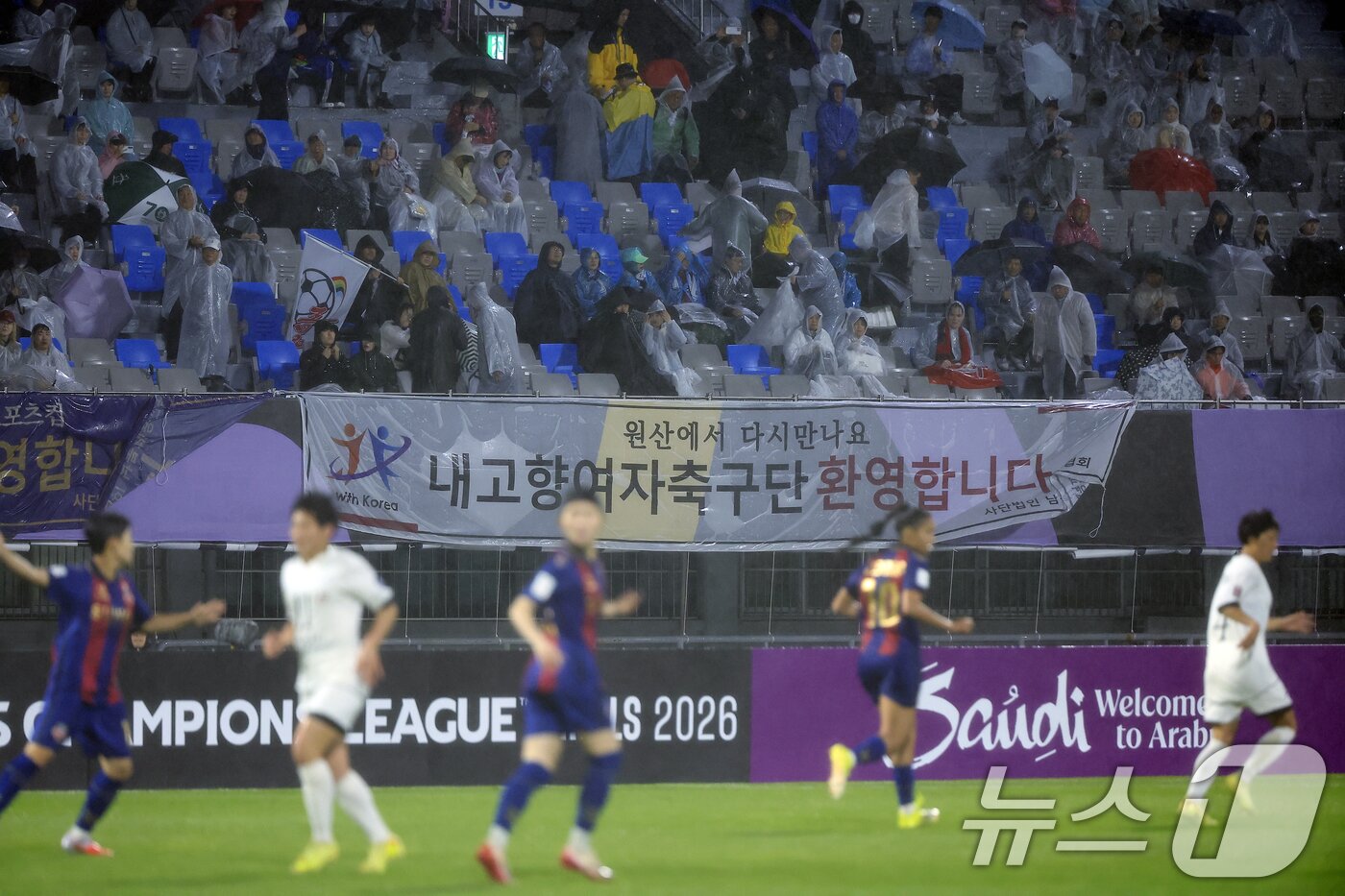 본문 이미지 - 20일 오후 경기도 수원시 장안구 경수대로 수원종합운동장에서 열린 2025-2026 아시아축구연맹(AFC) 여자 챔피언스리그(AWCL) 4강 수원FC 위민과 북한 내고향여자축구단의 경기에서 공동응원단 등이 '내고향여자축구단 환영합니다. 원산에서 다시만나요' 플래카드를 내걸고 '내고향여자축구단' 엠블럼 깃발을 흔들고 있다. 내고향축구단은 북한의 소비재 기업인 '내고향'이 지난 2013년 창단, 국제축구연맹(FIFA) 랭킹 10위에 오를 정도로 세계에서 실력을 인정받고 있는 강팀이다. 2026.5.20 ⓒ 뉴스1 박정호 기자
