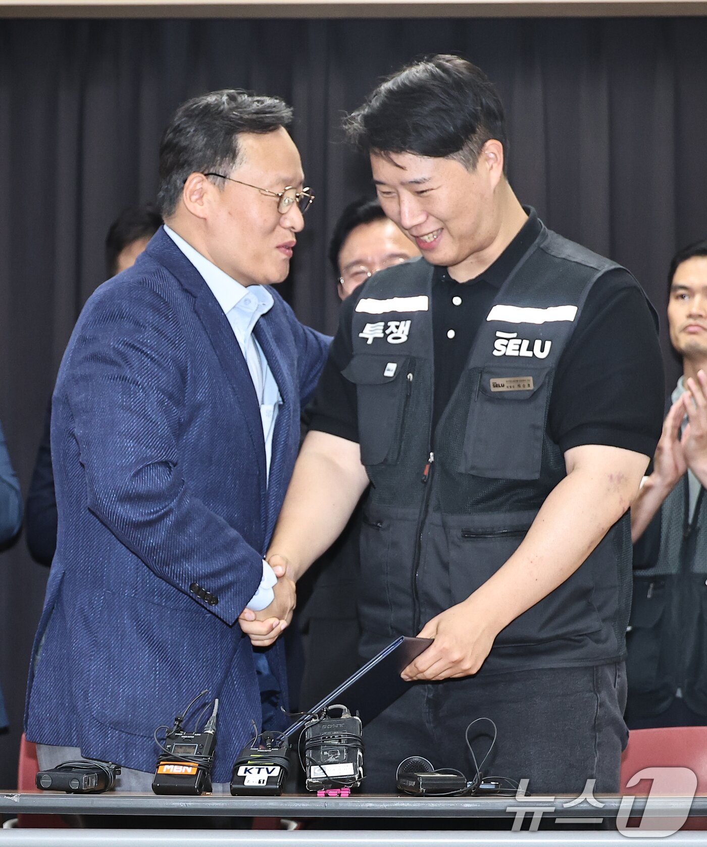 본문 이미지 - 20일 경기 수원시 장안구 경기고용노동청에서 열린 삼성전자 임금협상을 마친 후 여명구 삼성전자 DS(디바이스솔루션·반도체 사업 담당) 피플팀장과 최승호 삼성그룹 초기업노동조합 삼성전자지부 위원장이 잠정 합의안에 서명한 후 악수를 하고 있다. (공동취재) 2026.5.20 ⓒ 뉴스1 김영운 기자