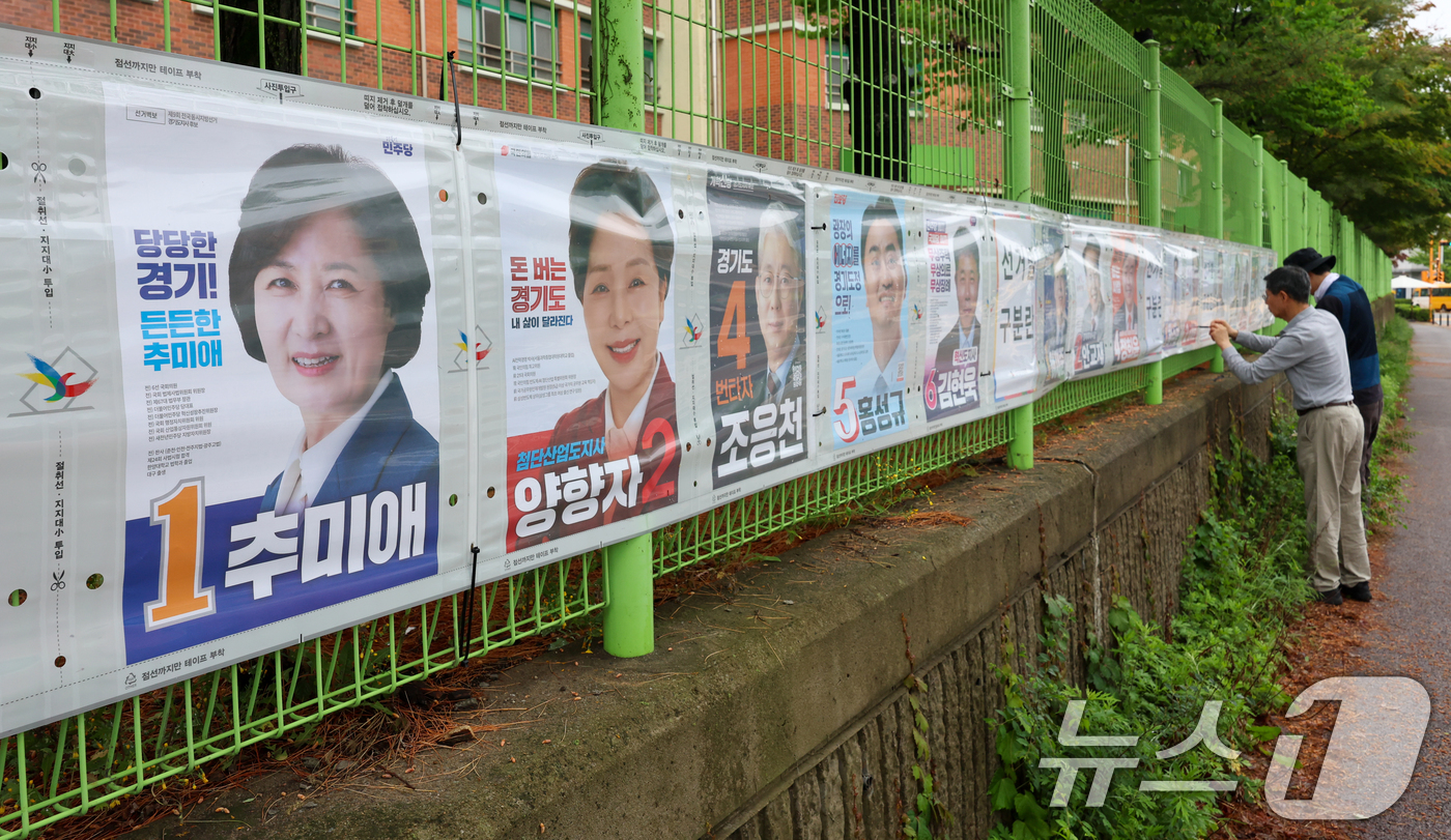 (수원=뉴스1) 안은나 기자 = 경기도선거관리위원회 관계자들이 제9회 전국동시지방선거 공식 선거운동이 시작된 21일 경기 수원시 팔달구 율현중학교 펜스에 경기도지사, 수원시장, 도 …